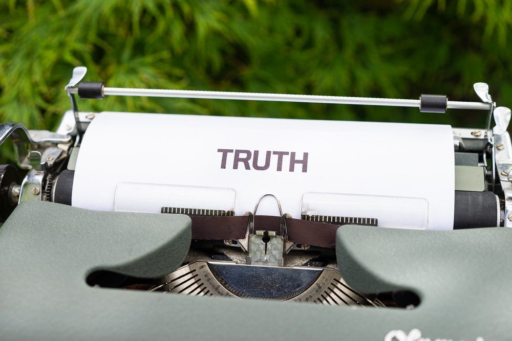 A typewriter, with a sheet of paper with the word Truth typed on it.