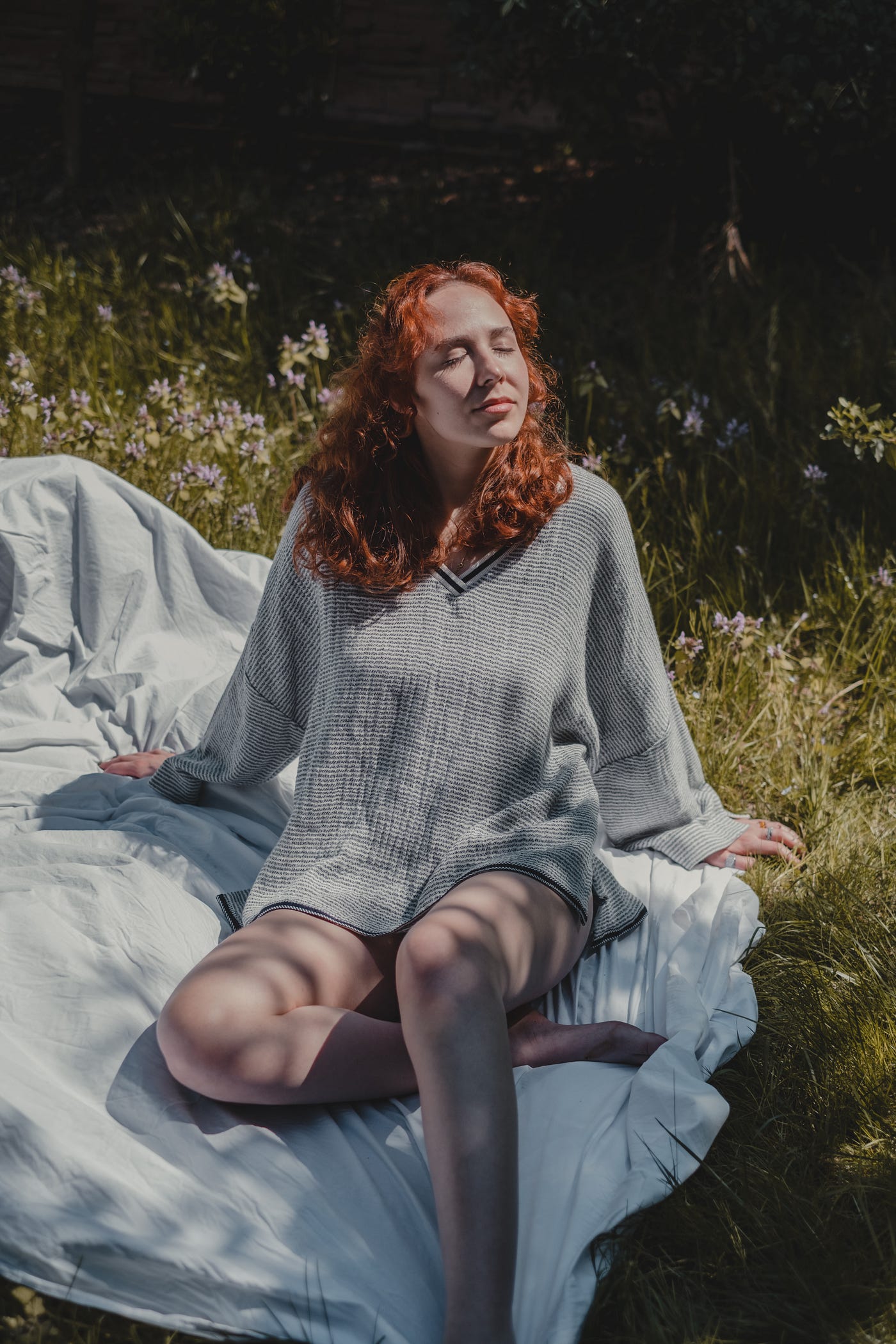 A ginger woman soaking in sunlight sitting on grass