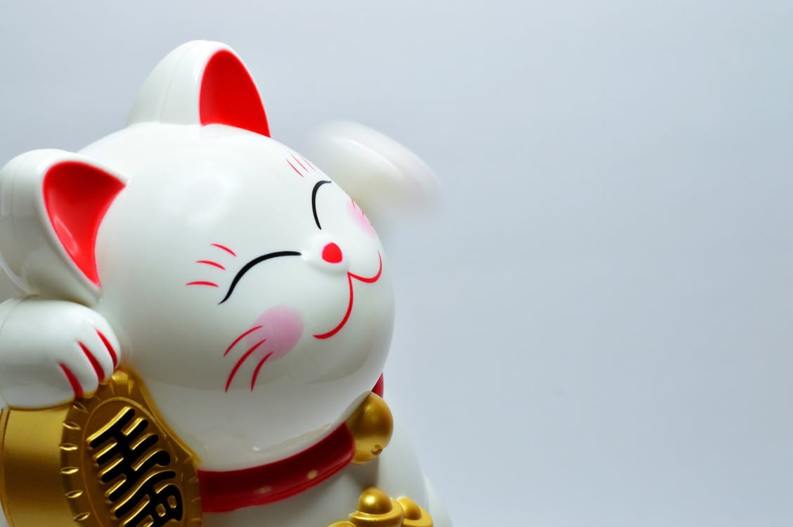 A lucky cat piggy bank smiling because its full of money.