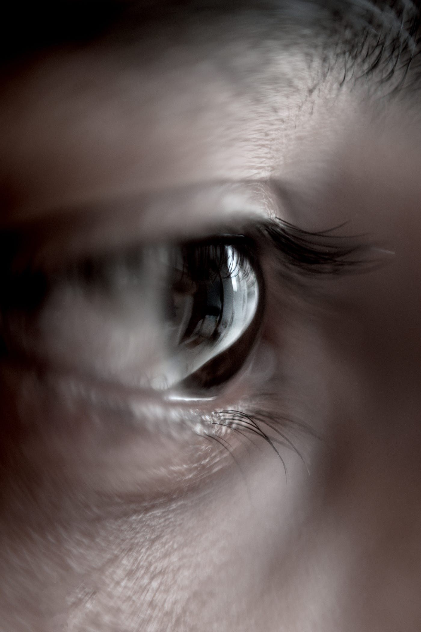 Close up on an eye, see from the side. The person has brown skin and brown eyes.