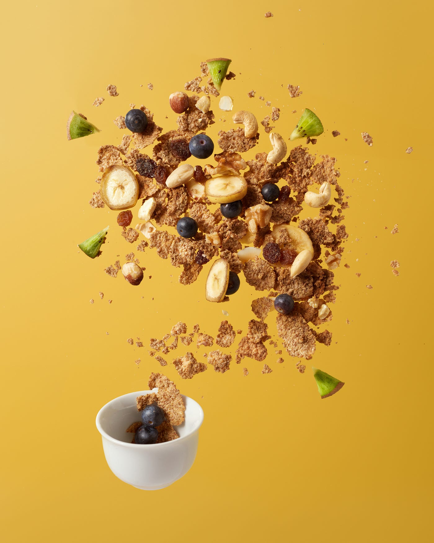 Cereal and fruits appear to spill upward from a small white bowl. ustard colored background. Calorie restriction alters methylation and causes changes that suggest slower aging.