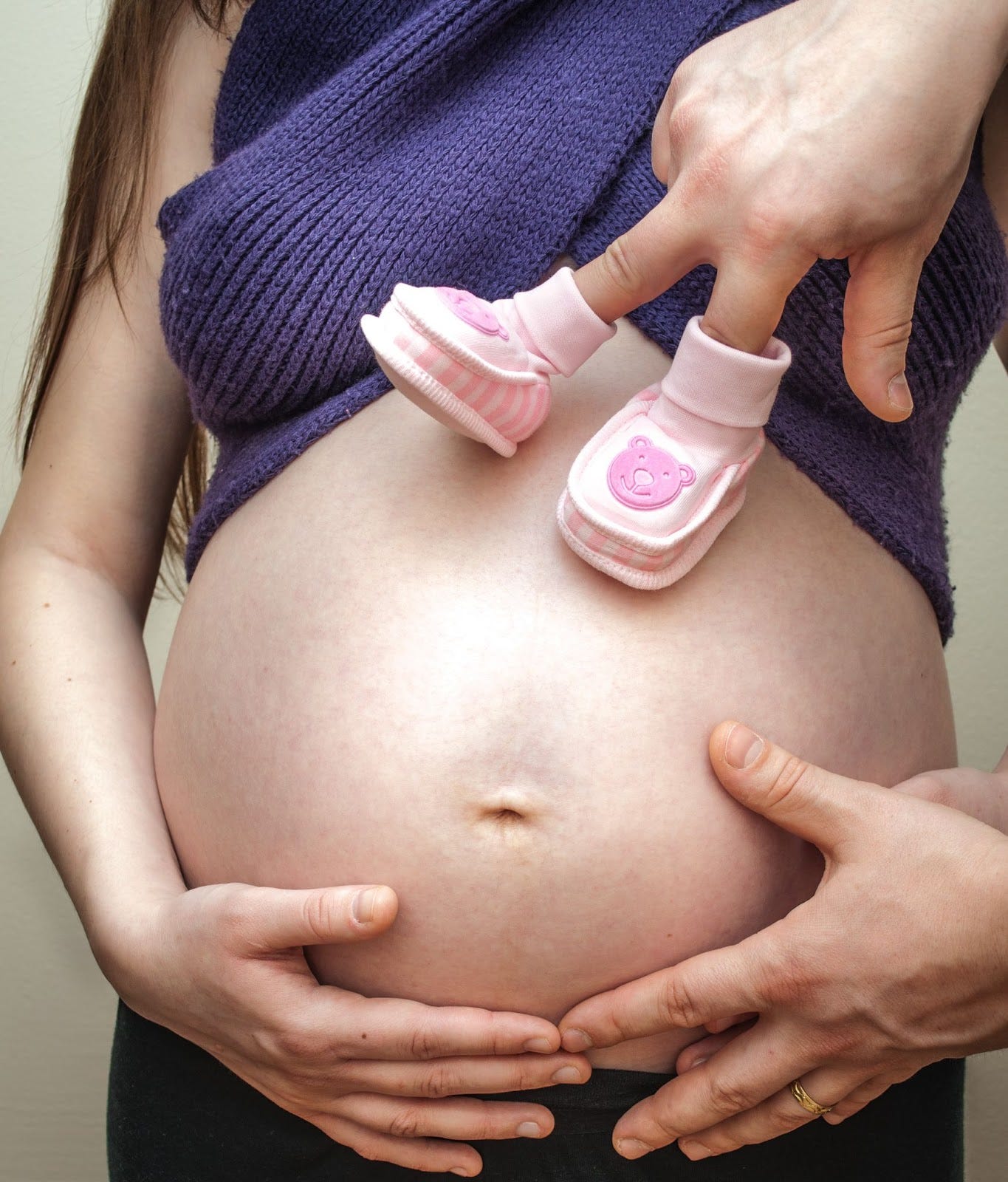 A pregnant woman and her husband holding her belly.