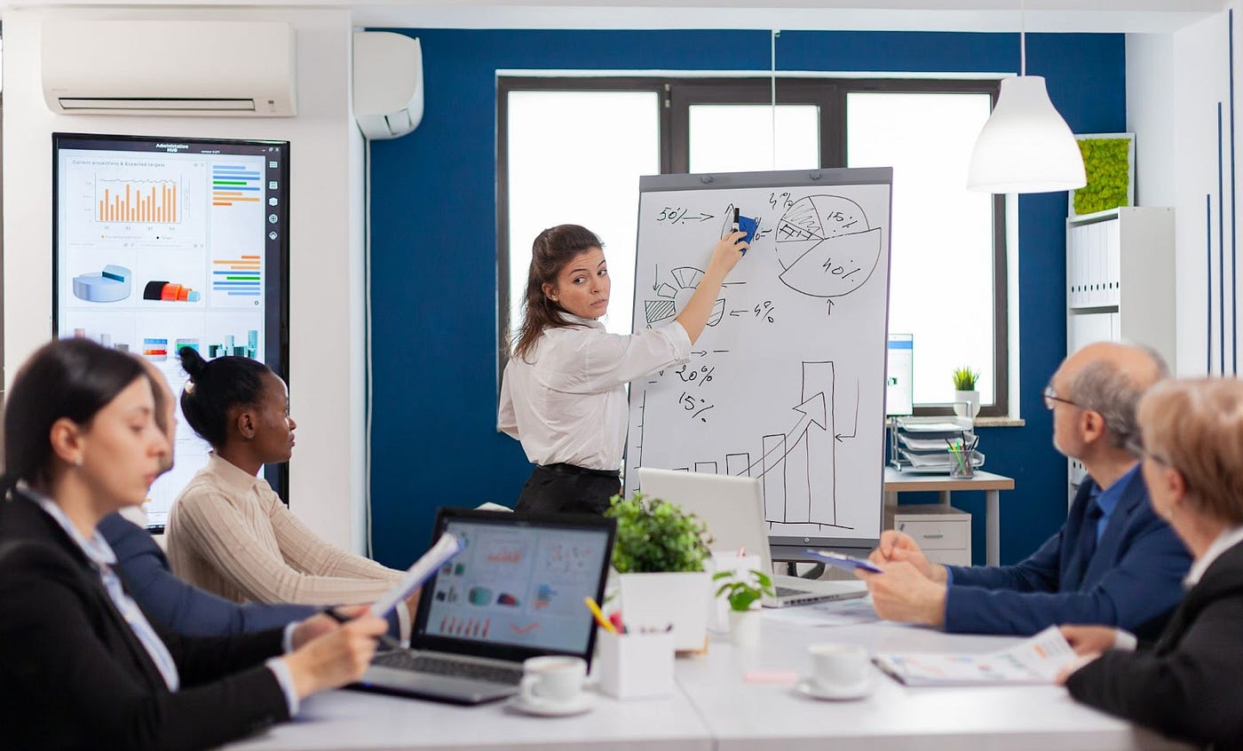 A woman drawing graphs on a whiteboard in a meeting