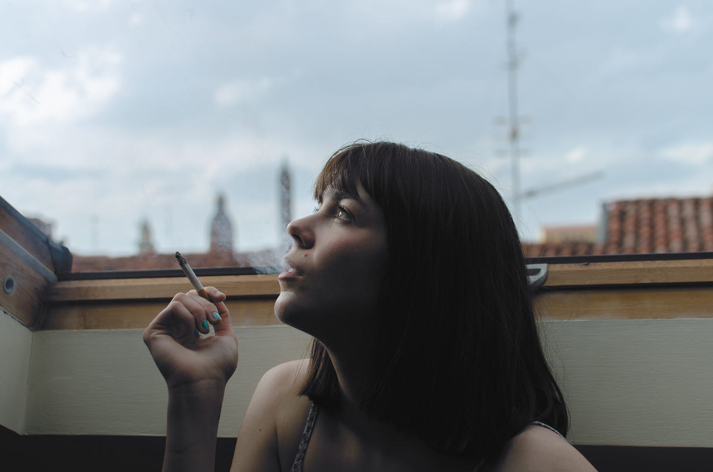 Non-ejaculation practice. A womanblowing out smoke from inhaling a smoke.