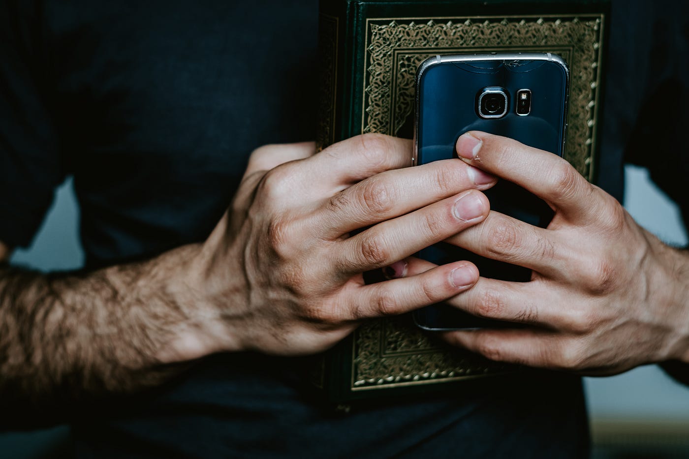 Hands holding a cell phone and notebook.