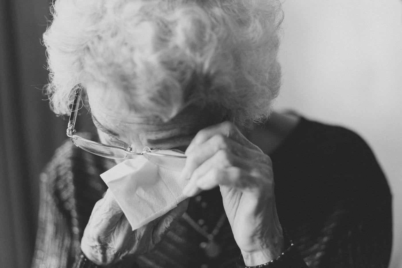 A black and white image of an elderly lady crying.