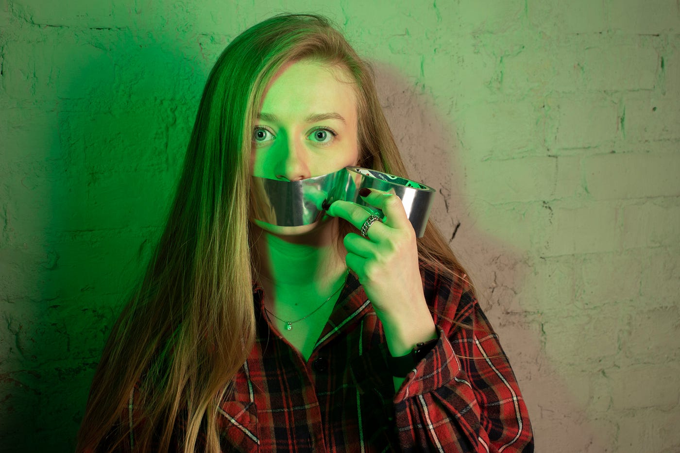 A girl takes duct tape off of her mouth.