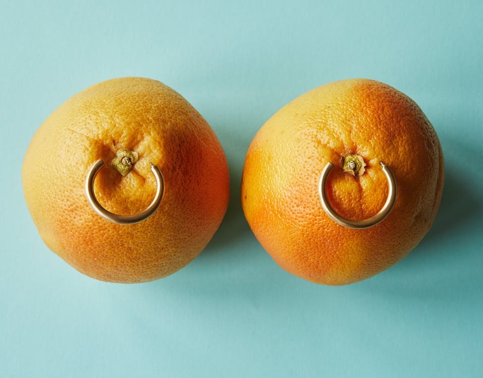 Duas tangerinas com piercings no meio contra um fundo verde-azulado.