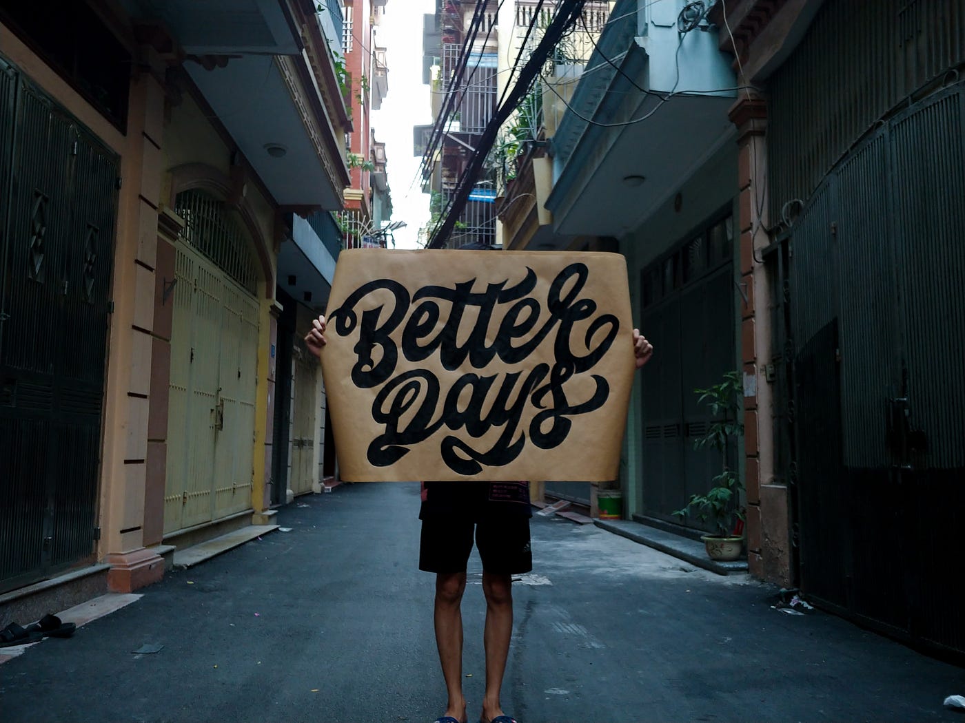 Person holding a sign that reads, “Better days”
