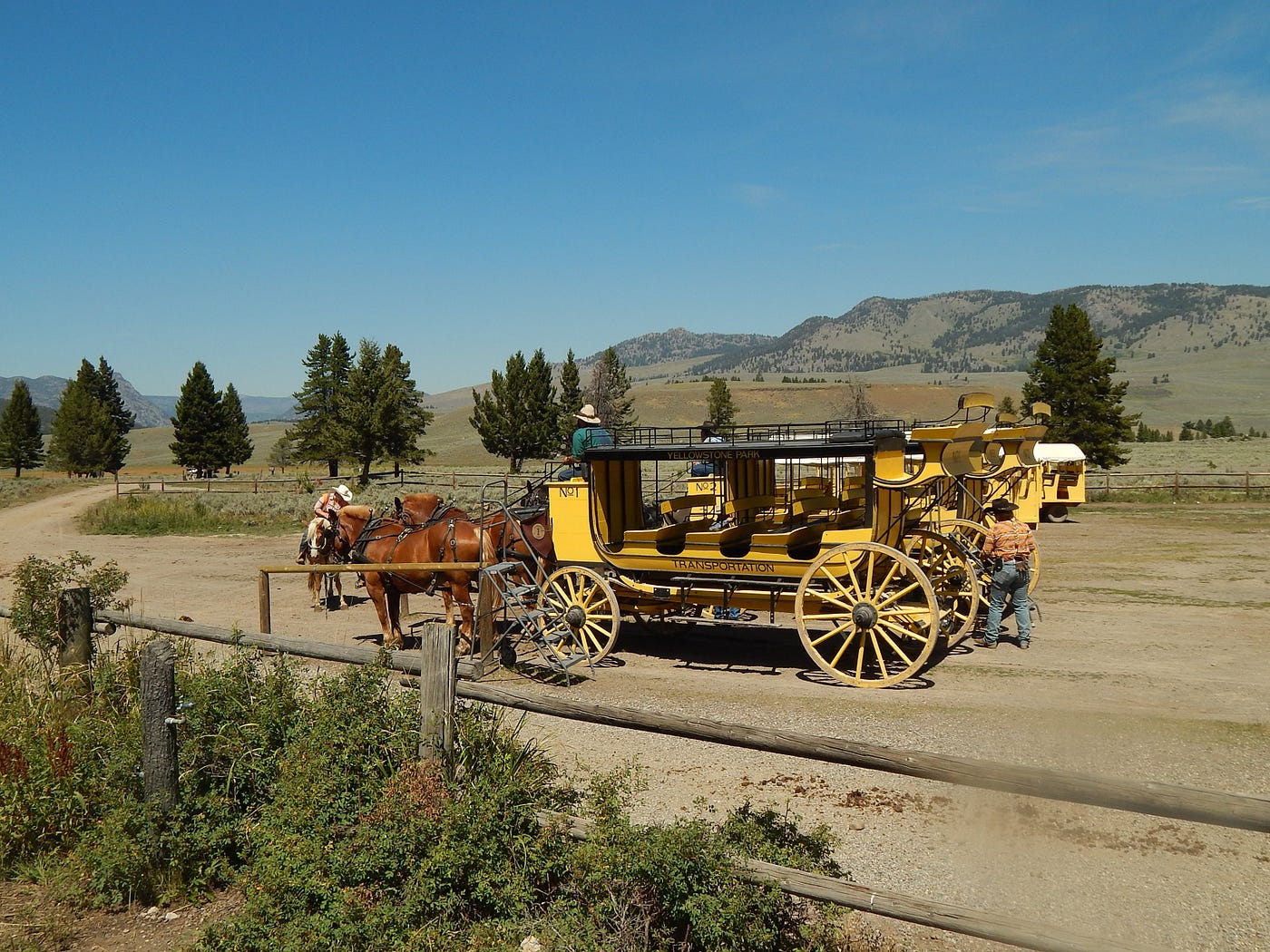 A scene depicting pioneers in the American west. A horse-drawn wagon on a dirt trail.