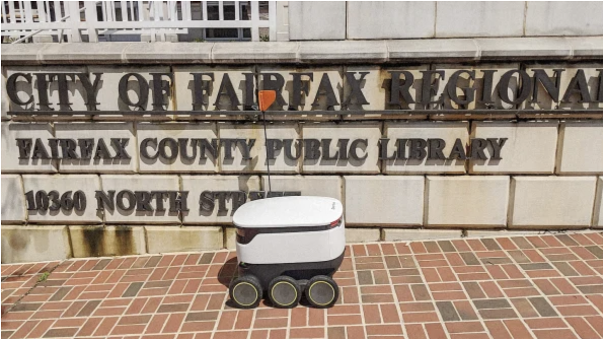 A Starship robot pictured in front of the City of Fairfax County Public Library.