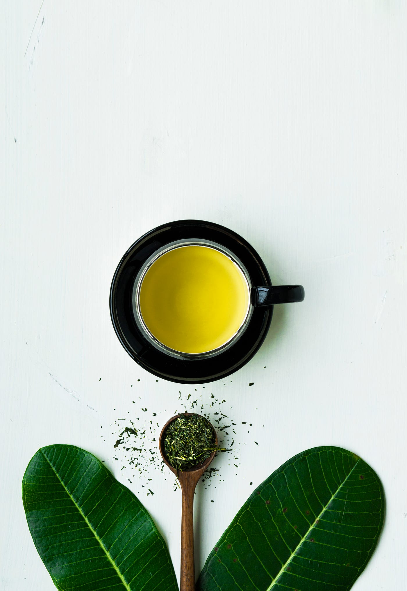 A cup of green tea in a black cp, as seen from above.