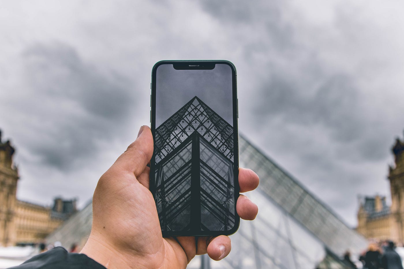 Man with a smartphone taking a photo of a building. 