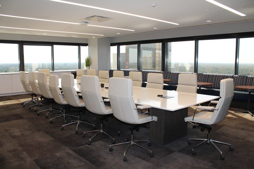 A large conference room showing a table surrounded by 16 chairs, all empty