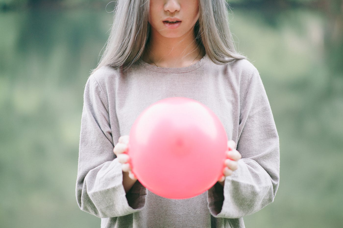woman with long silver hair holding pink beach ball