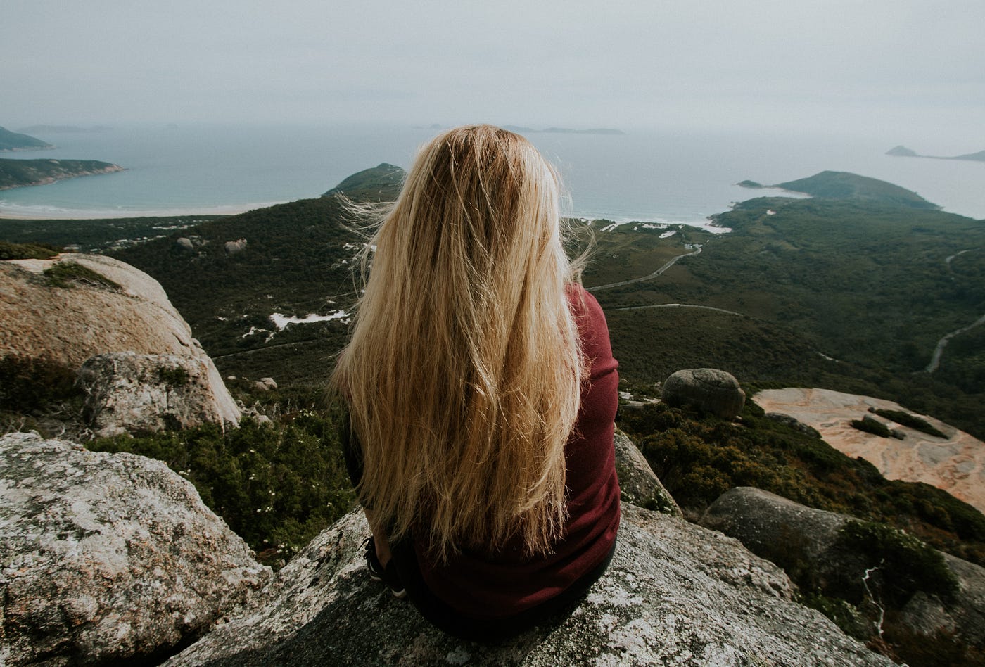 Girl sitting on a mountain overlooking a beautiful view.