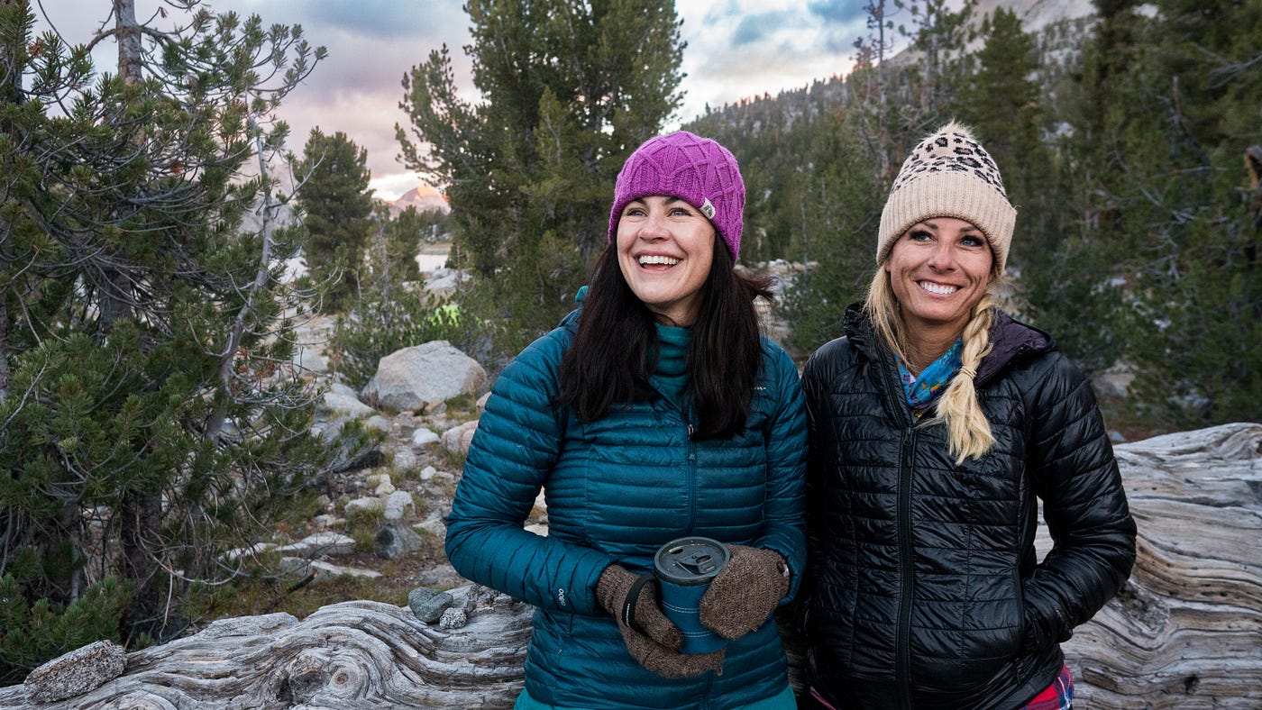 A brunette and blonde women hiking in the mountains.