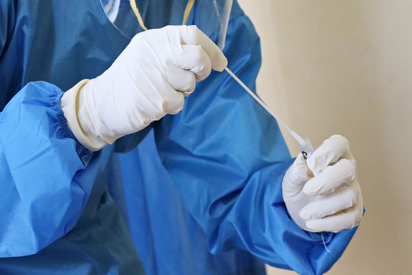 A healthcare worker dips a long swab into a vial of media.