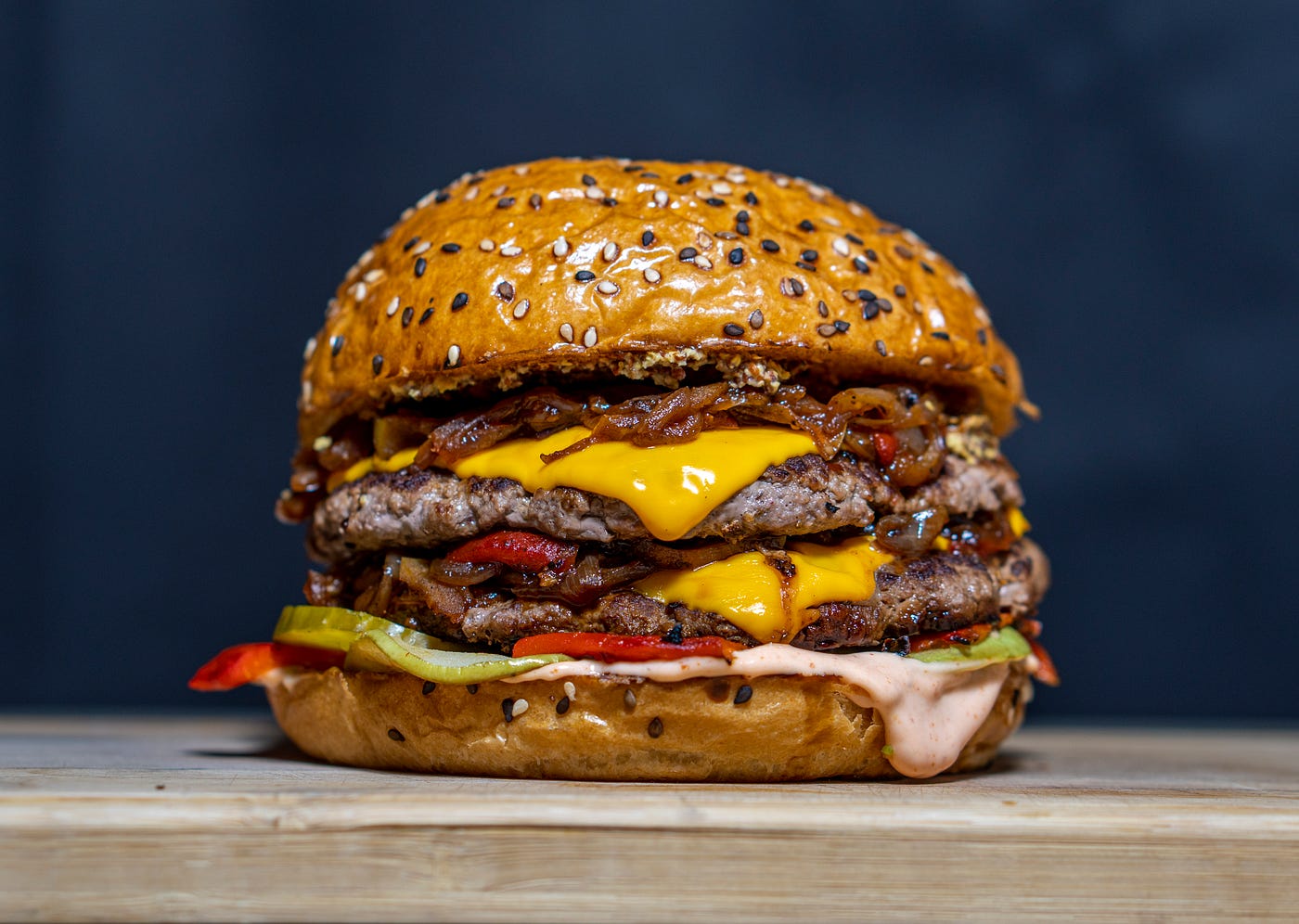 A cheeseburger with two beef patties on a wooden table.