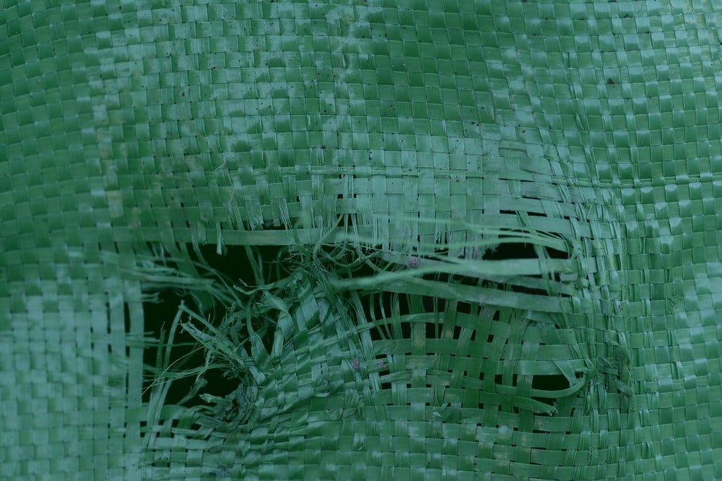 Close-up image of a damaged green threaded jumbo bag with almost half of the threads damaged