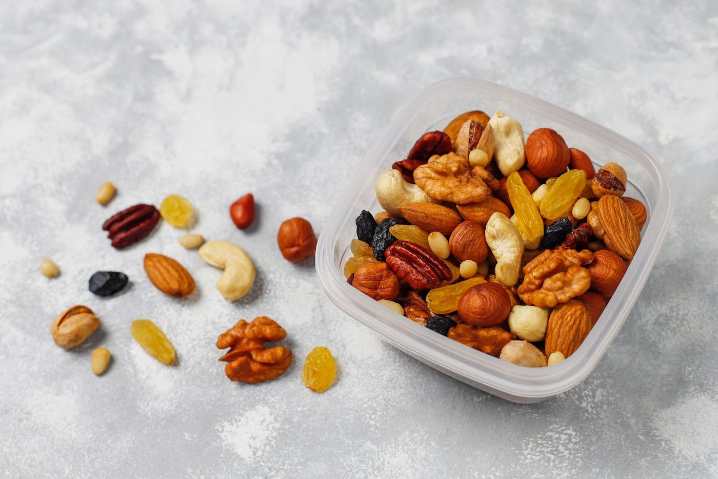Nuts like cashews, walnuts, almonds, raisins etc. in a bowl and on the table.
