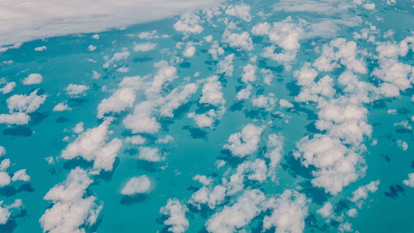 puffy clouds over a bright blue sea viewed from above