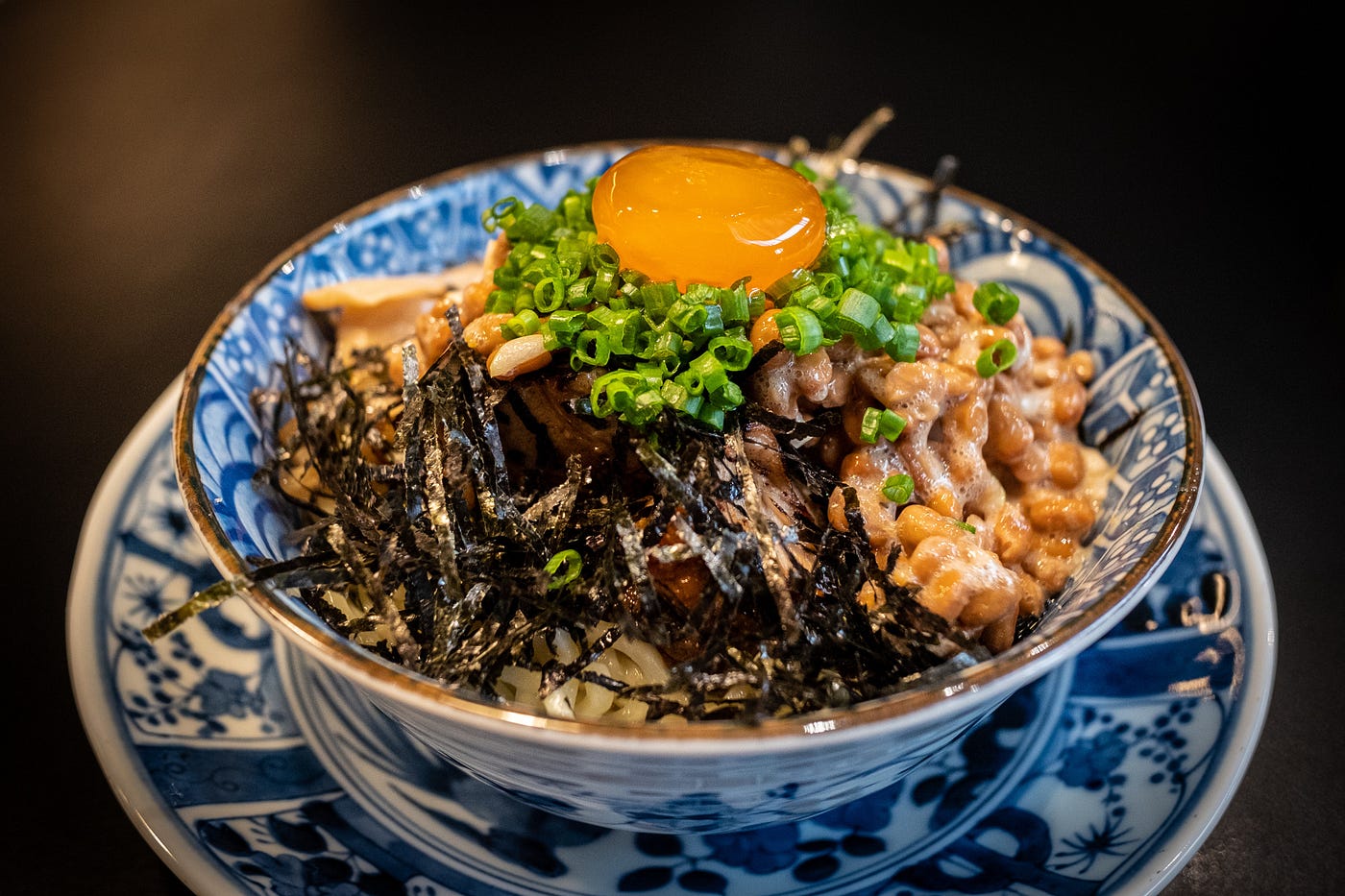 Natto in a blue bowl on a blue plate.