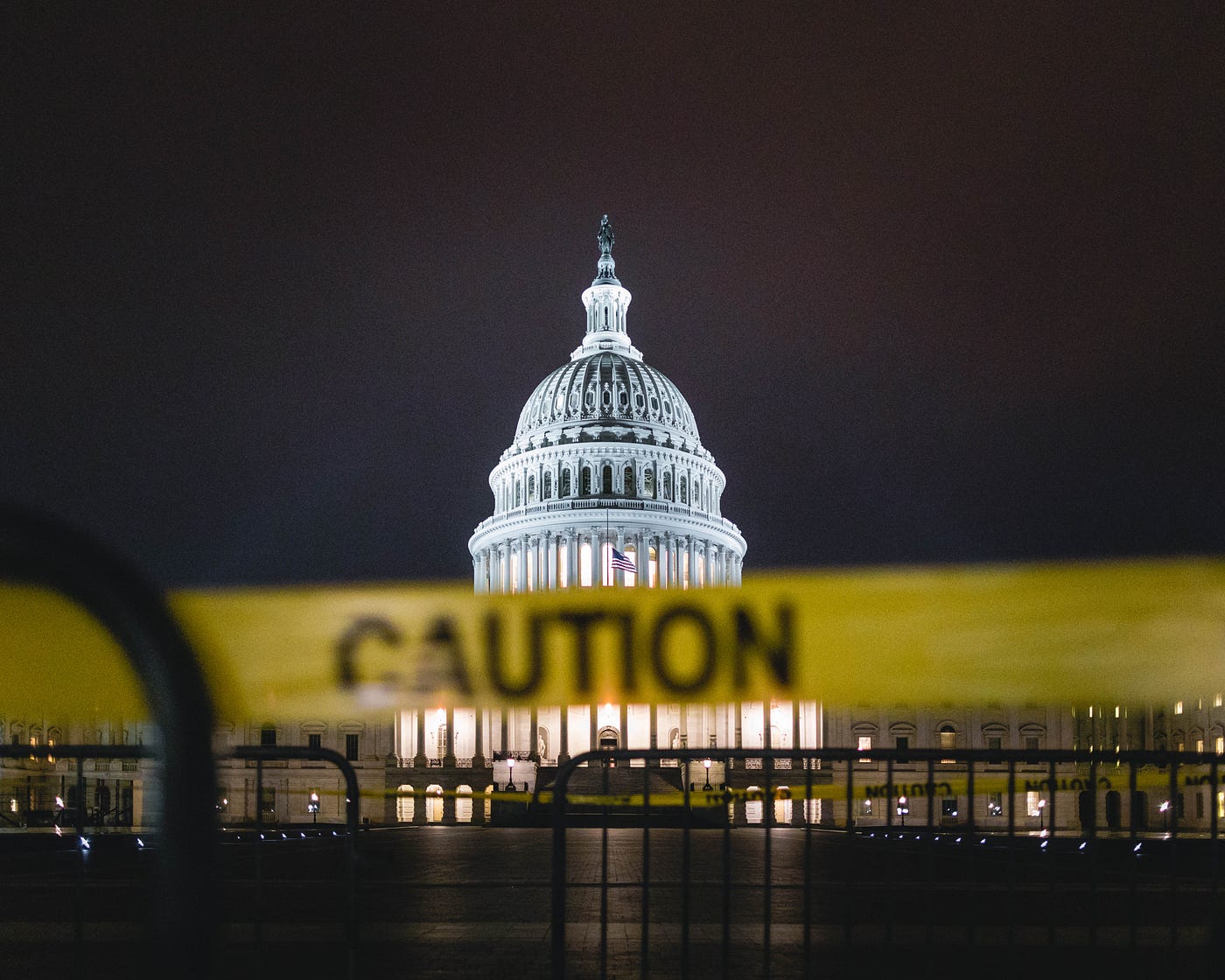 Washington, DC Capitol building at night, with a yellow caution tape in the foreground.