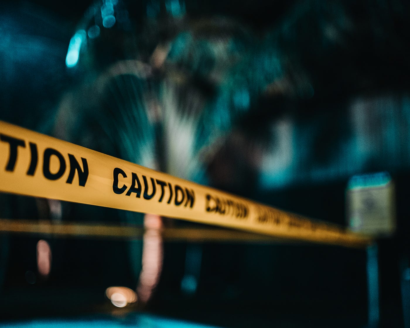 Caution tape, yellow with black letters, spans the horizontal widdth of this otherwise blurred image.