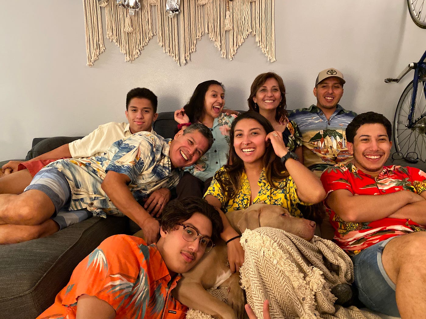 The Mancilla family all laughing and wearing Hawaiian tee shirts for a family group pic on a couch.