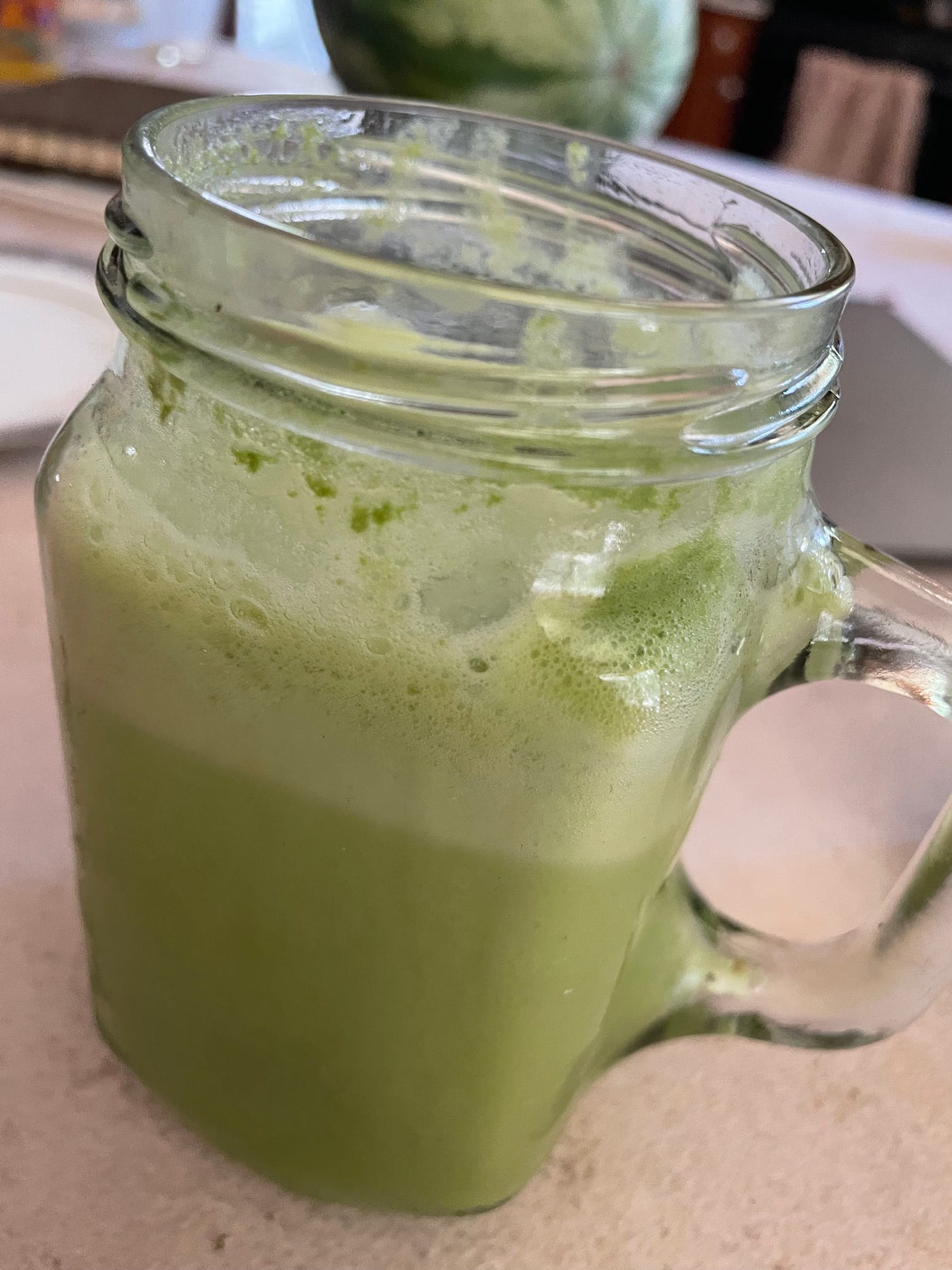 A close up view of a glass of green lemonaide.
