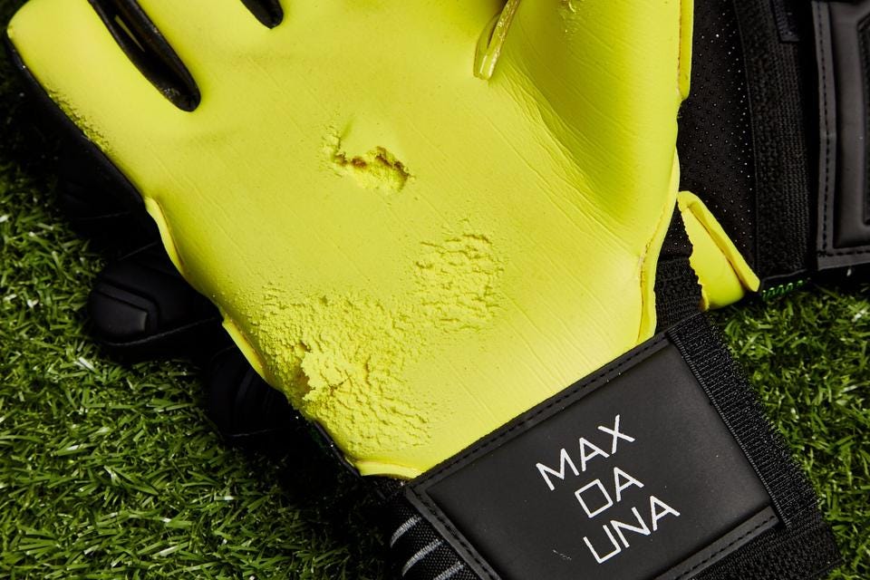 Abrasions in the bright yellow latex palm of a goalkeeper glove.
