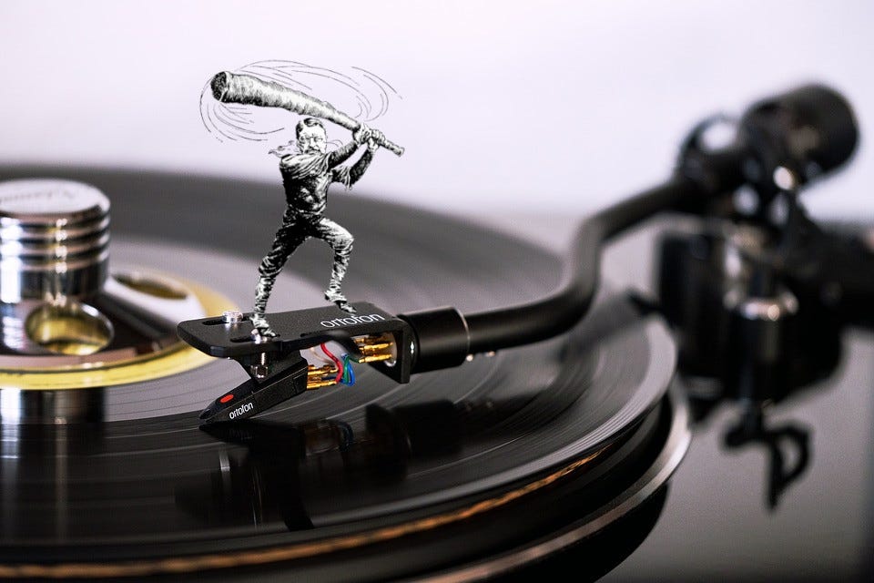 A turntable with a caricature of Teddy Roosevelt as a trustbuster, standing on the tonearm, wielding his ‘big stick.’