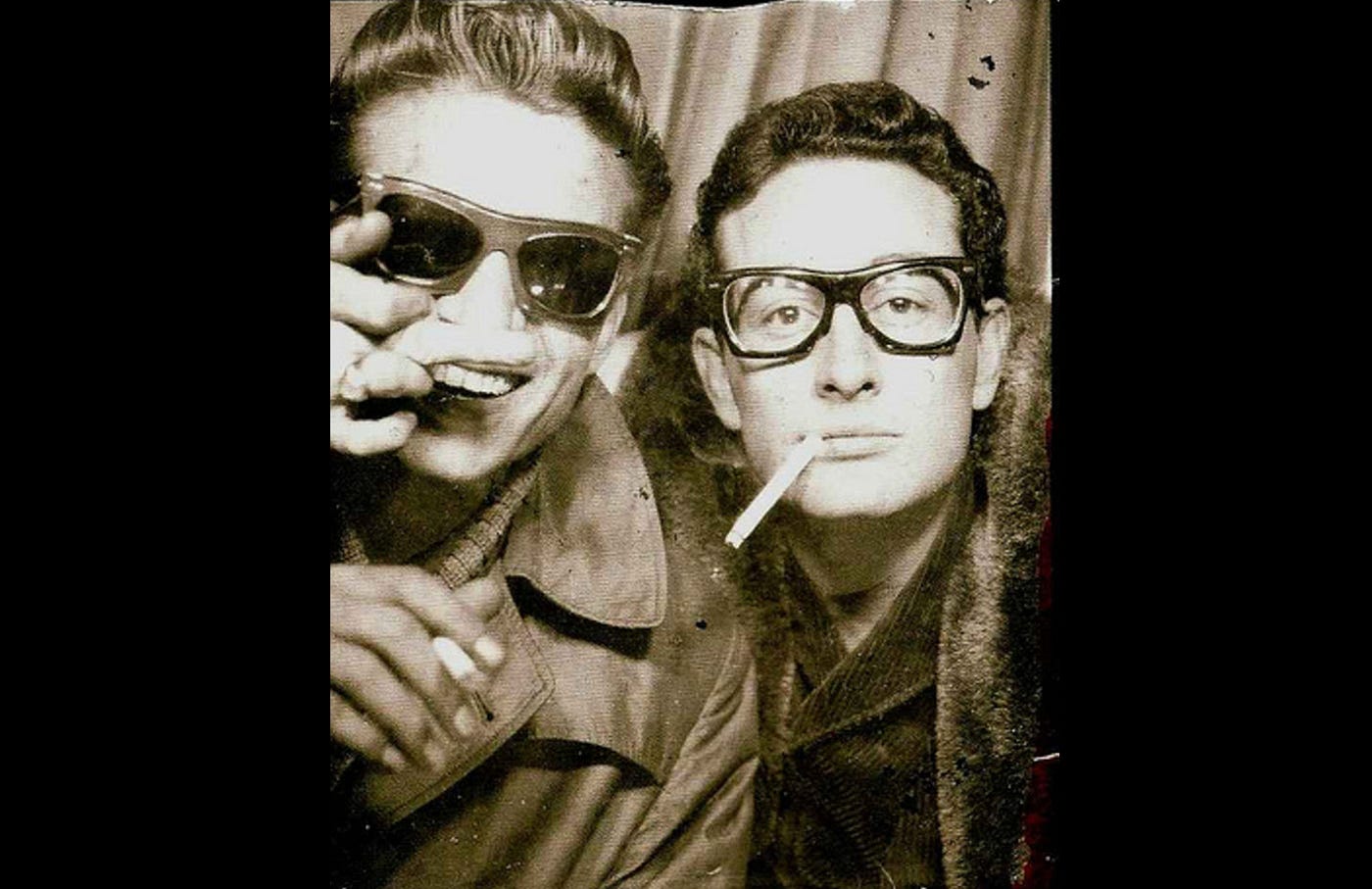 Image of a black and white photograph of Waylon Jennings and Buddy Holly in a photo-booth in Grand Central Station, New York City, in January 1959.