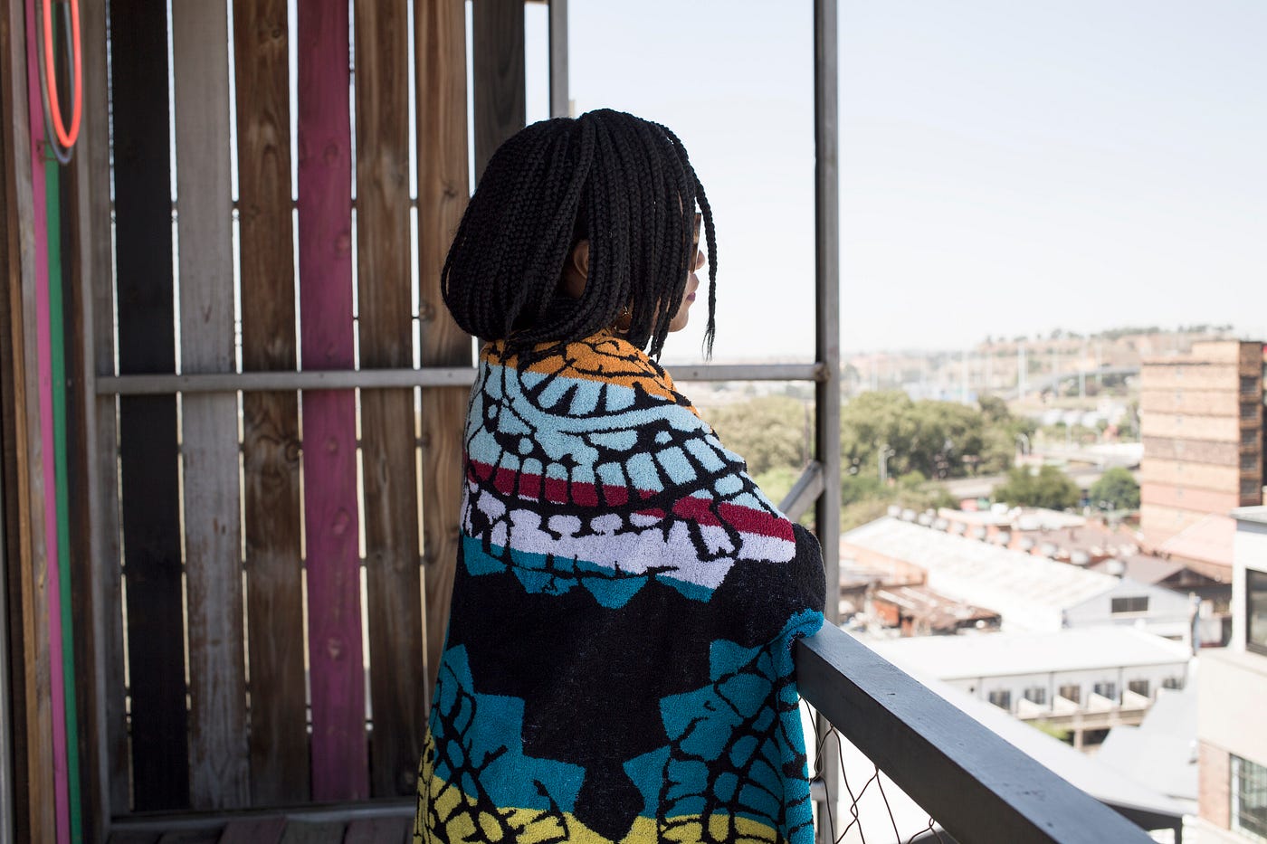 A photo of a young woman on her balcony looking outside.