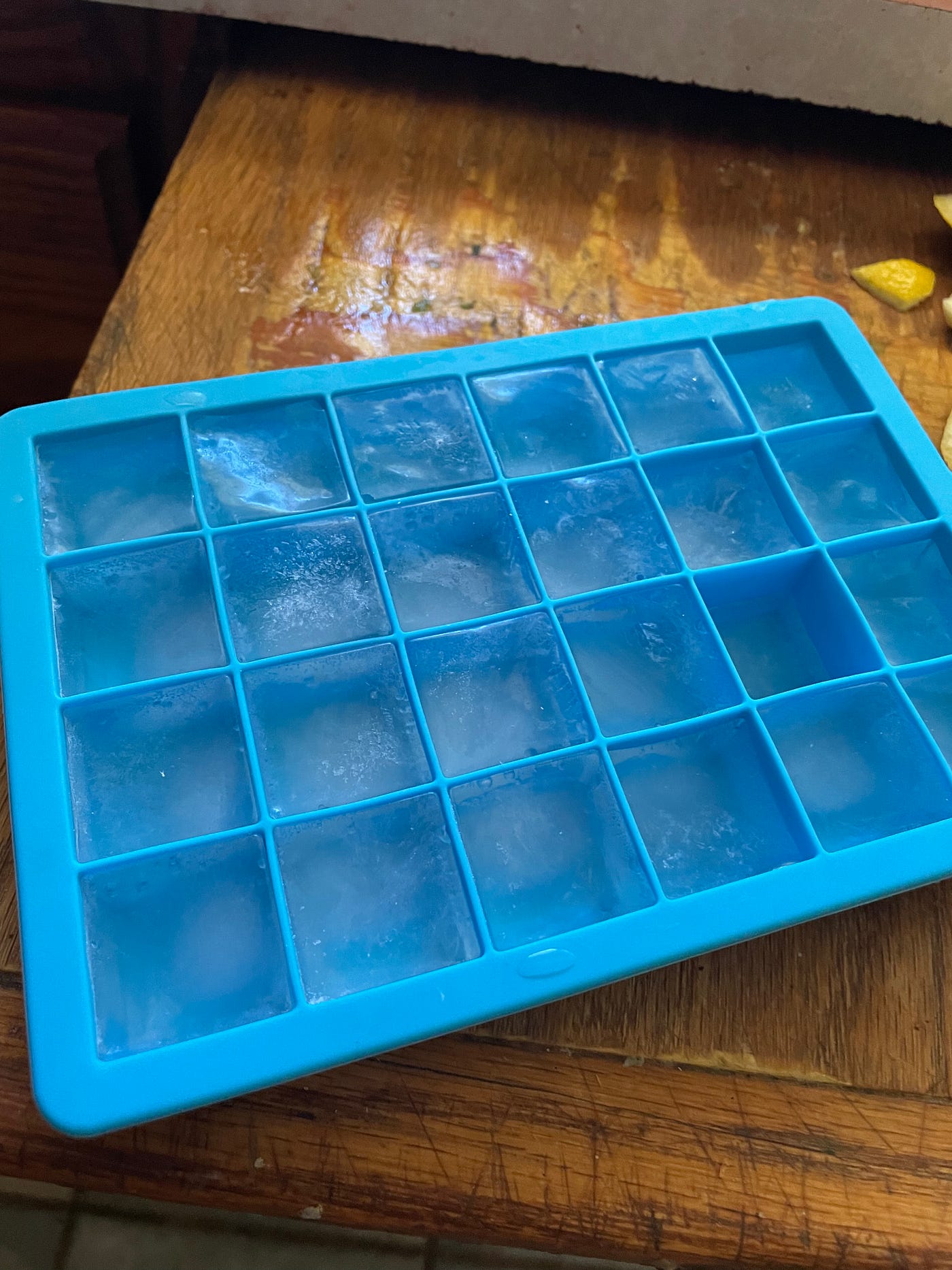 A blue ice cube tray on a cutting bored full of ice.