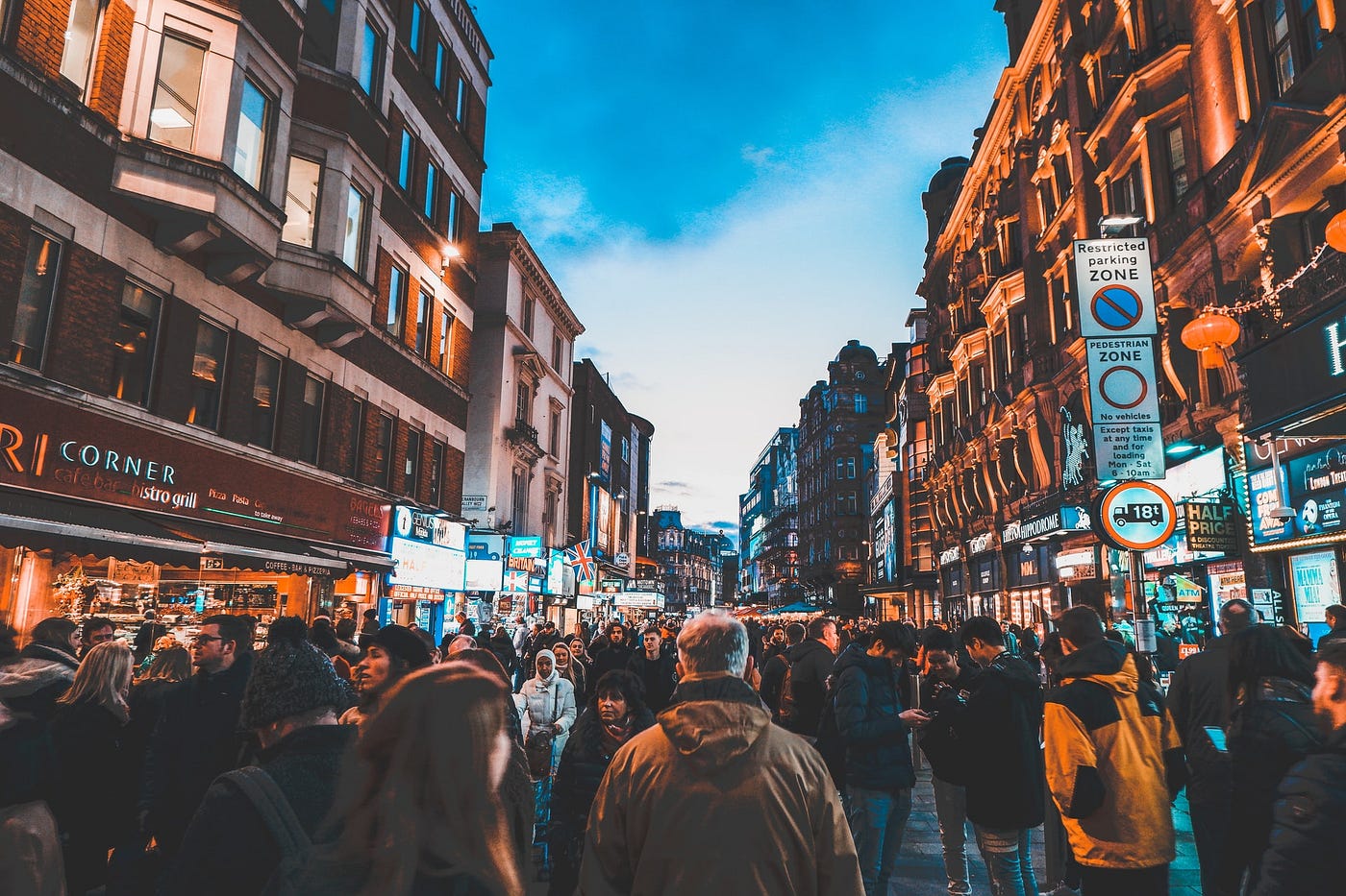 Crowd of people walking in all directions in a busy shopping district.