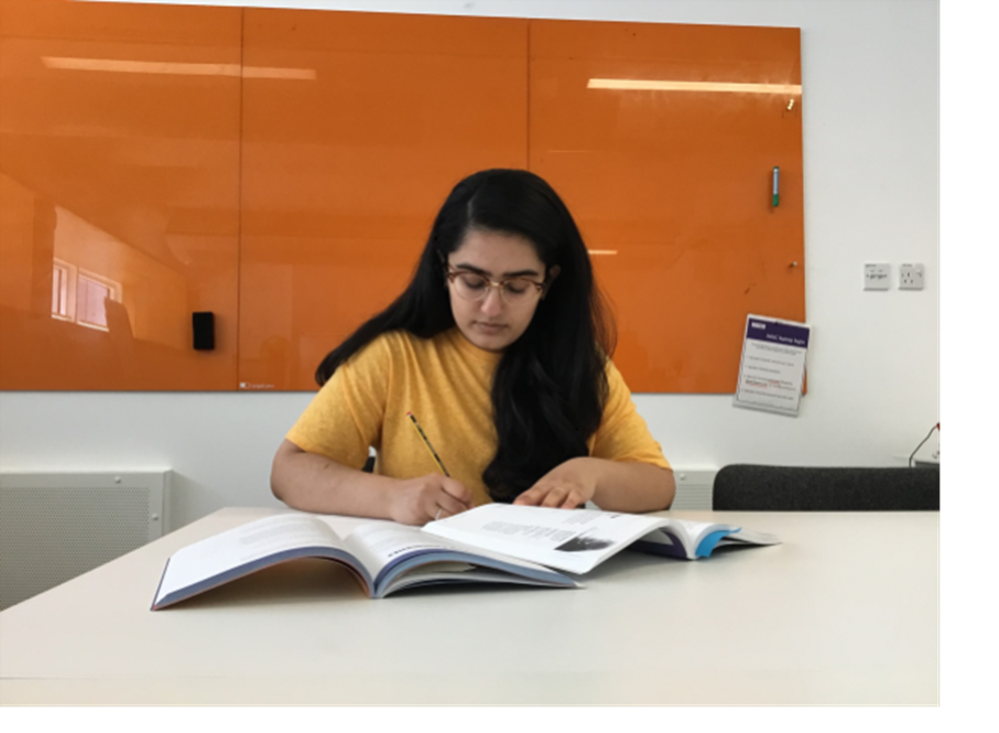 A girl taking notes from a textbook.