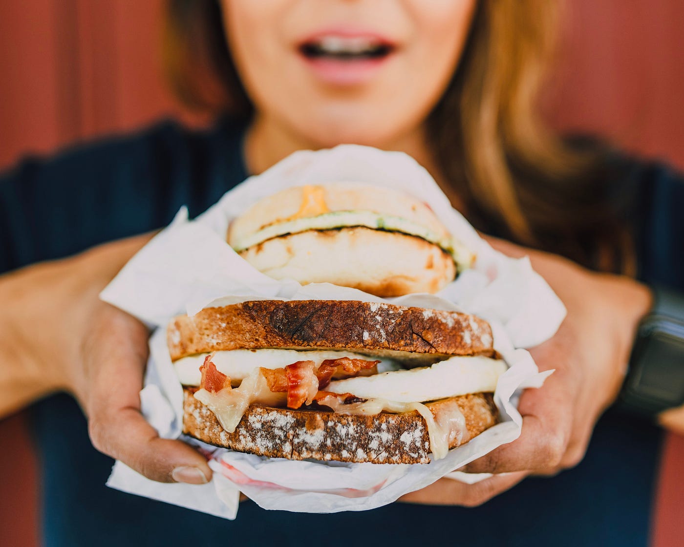 photo of women holding large sandwich up to eat