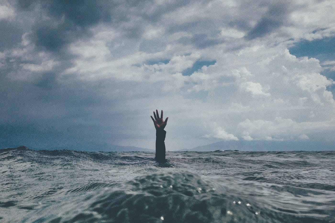 Person drowning in the sea, only hand and arm are out