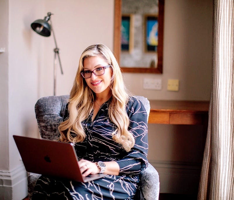 Military Spouse Lee O’Driscoll sits in a lounge chair with a laptop open on her lap.