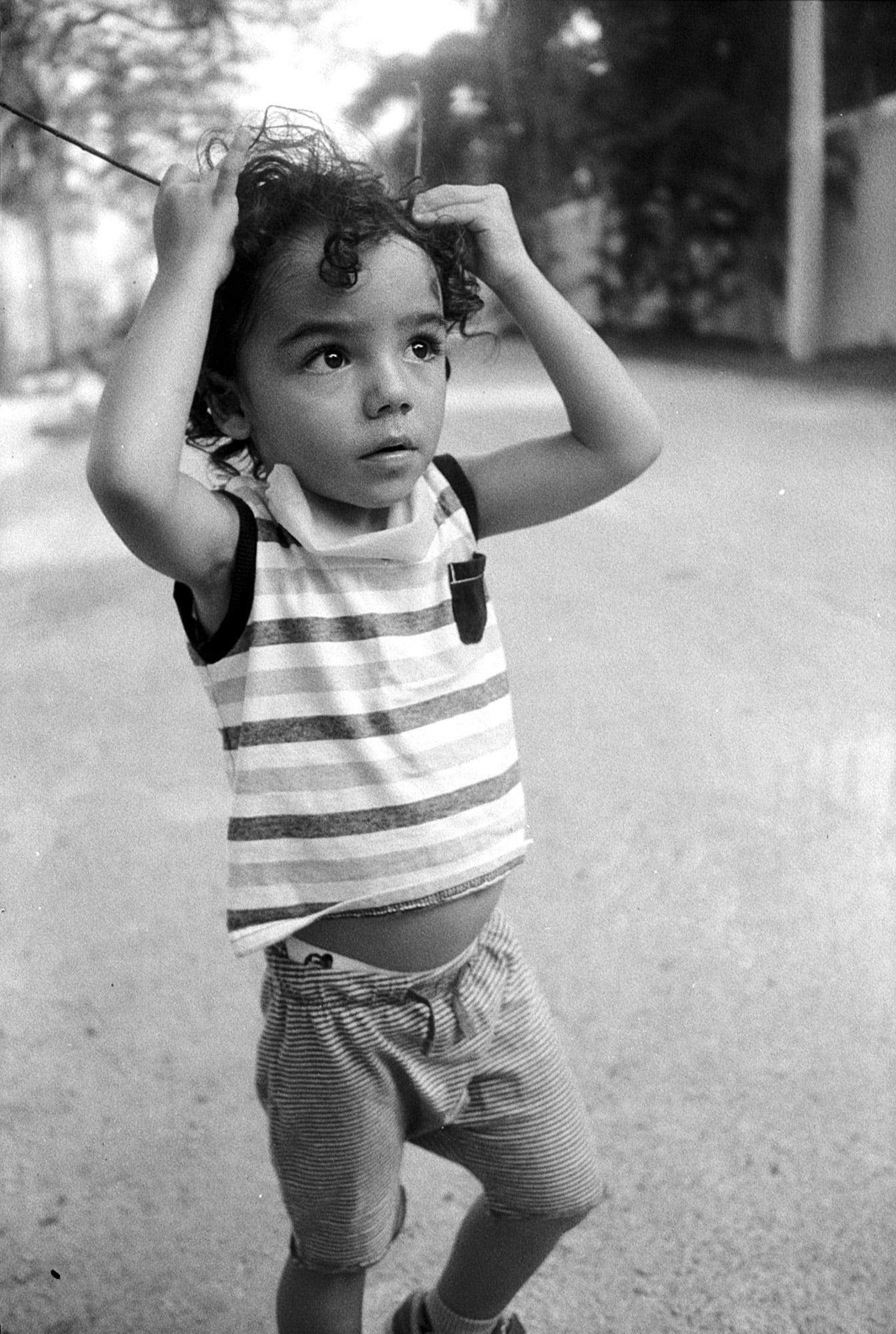 A little boy with curly hair looks to the sky.