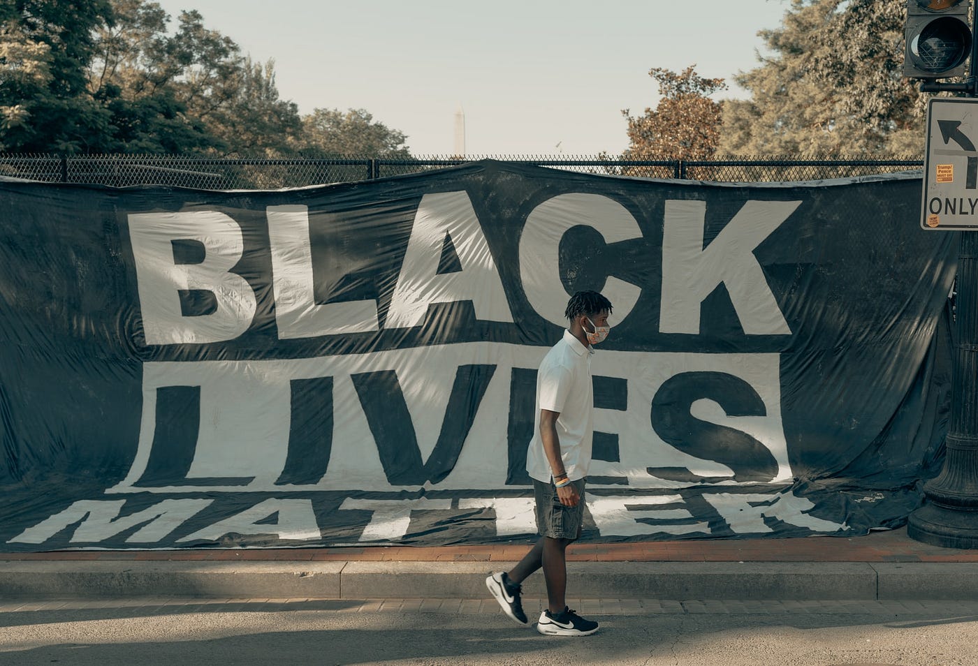 Man walks in front of a Black Lives Matter flag.