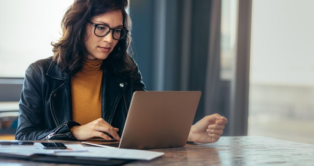 Asian woman working laptop at contemporary office in casual attire