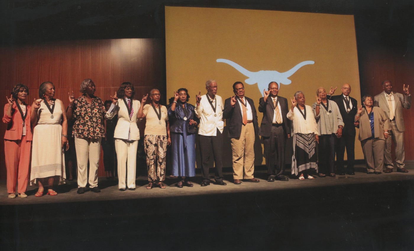 The Precursors use the Hook ’em Horns hand sign on stage at the UT Austin campus.