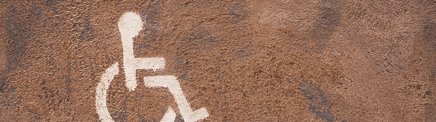 The symbol with the icon of a person in a wheelchair is painted in white on a wall of bronze tones.