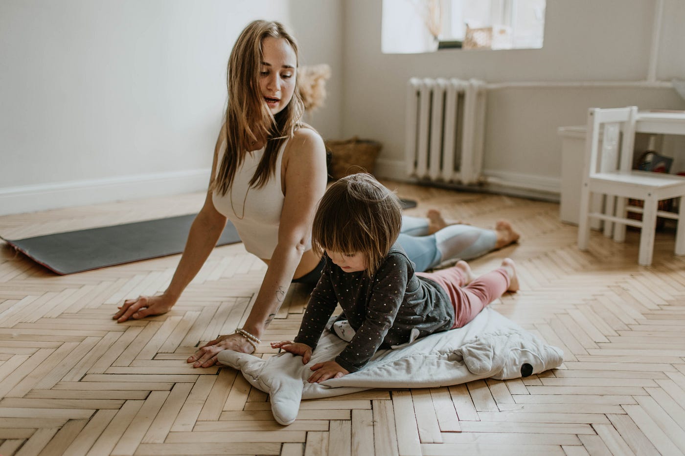 Woman and young toddler on the floor doing upward facing dog
