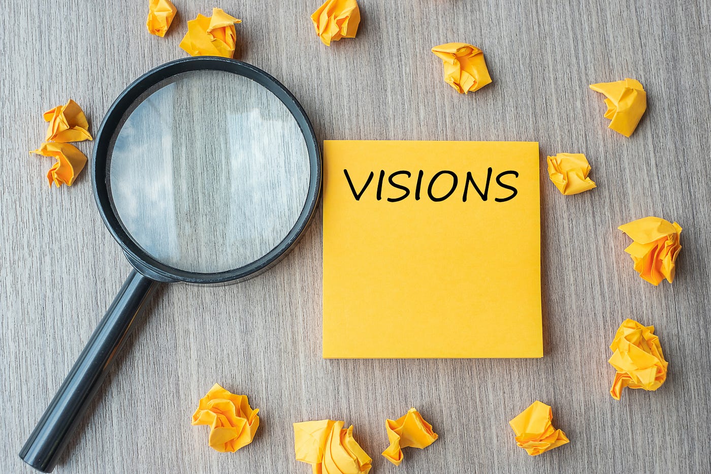 A picture of Magnifying glass with crumbled sticky notes trying to show the confusion with ‘Visions’ written on one.