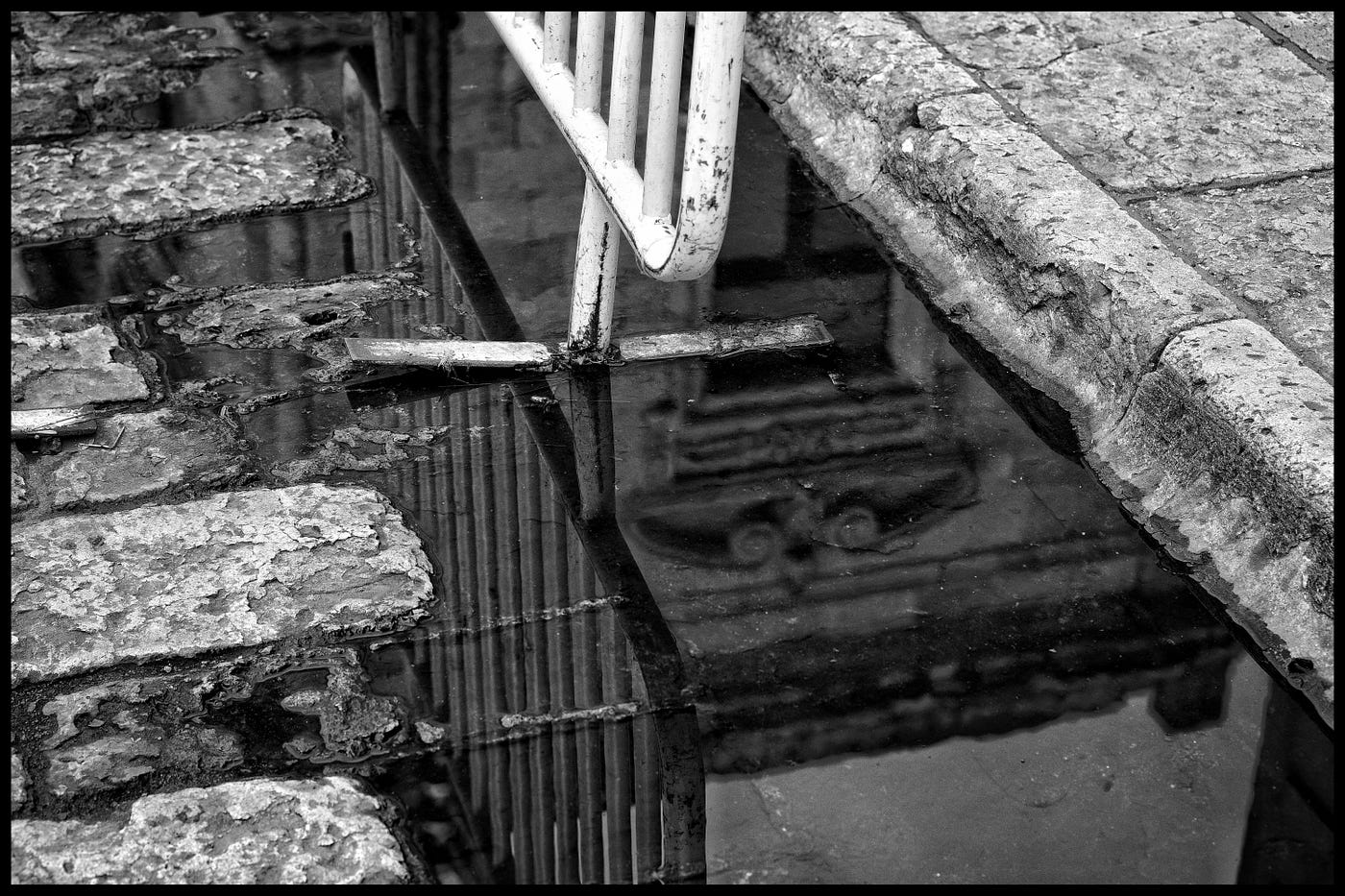 An abstract view street, water reflections, and curb with a hint of railing.