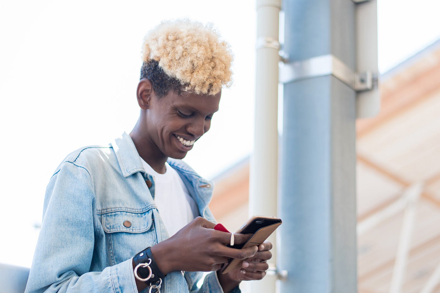 A side view of a non-binary African American person using their smartphone.